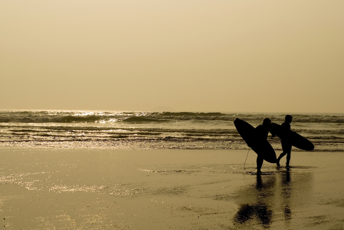 Two surfers get ready to surf on Polzeath beach Cornwall