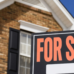 Home for sale - a sign in front of a brick house