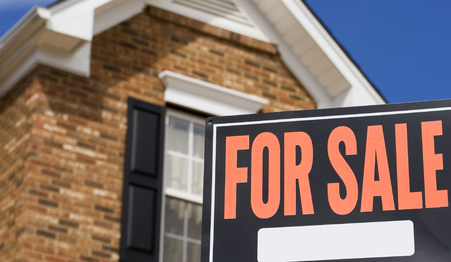 Home for sale - a sign in front of a brick house