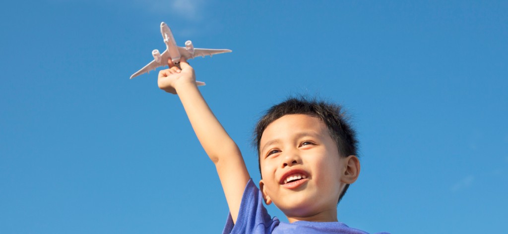 little boy with toy plane against blue sky. concept for plan to move abroad with child