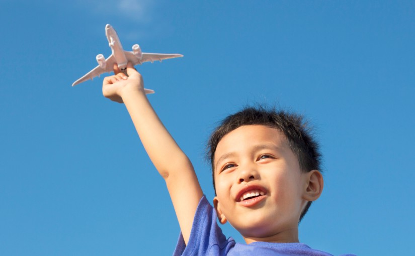 little boy with toy plane against blue sky. concept for plan to move abroad with child