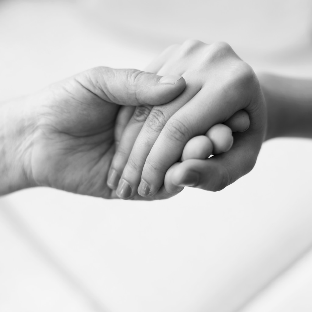 black and white depiction of two people holding hands for comfort and security