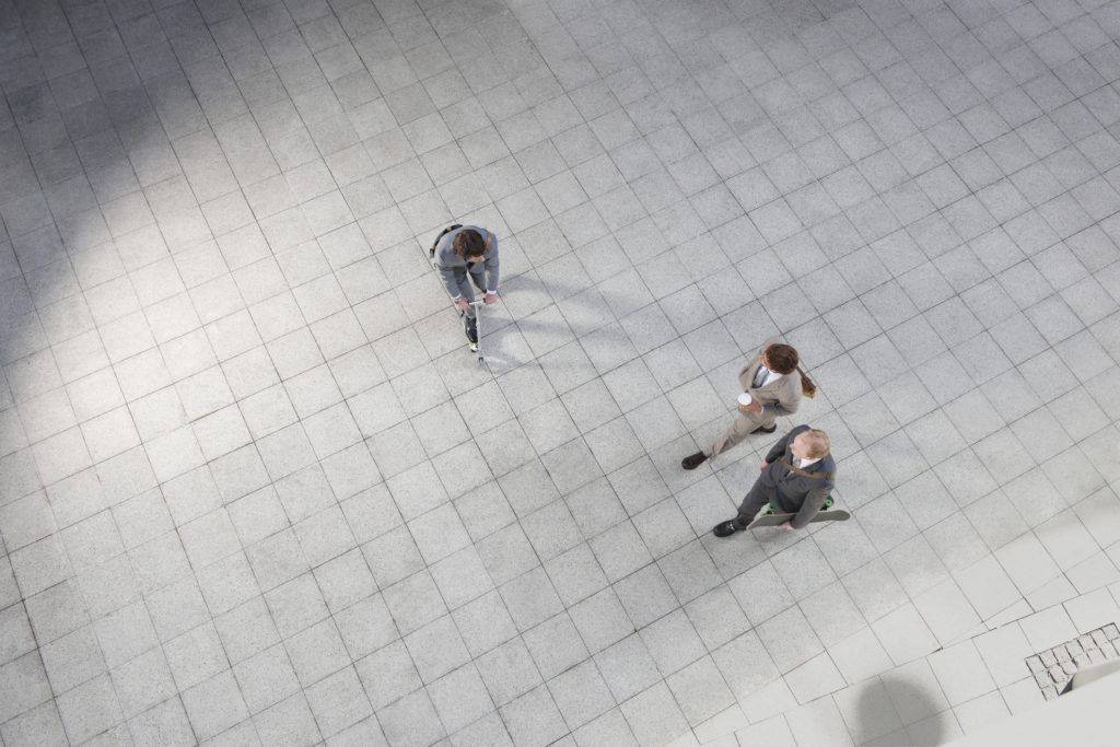 Businessman riding scooter in office courtyard