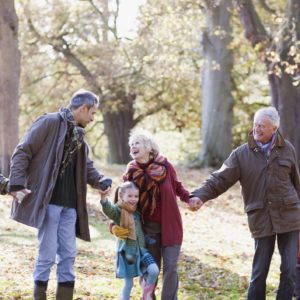 Extended family holding hands and walking in park
