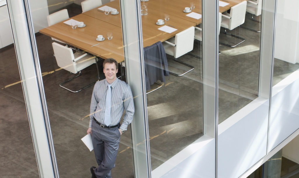 businessman leaning against window in conference room