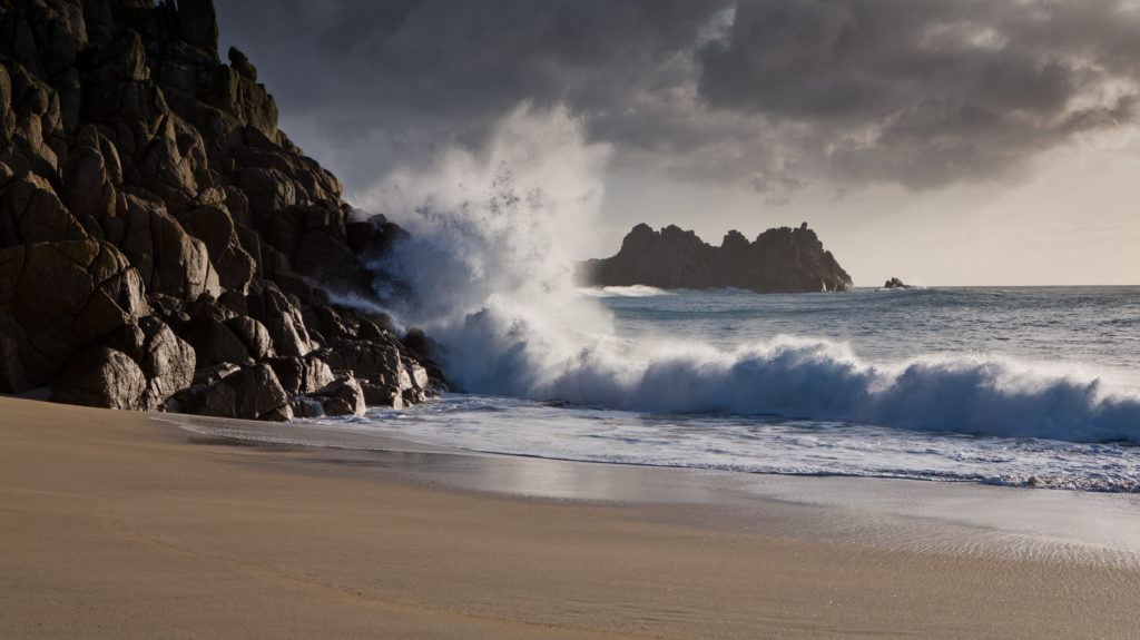 waves crashing against the rocks at Porthcurno Cove, Cornwall.
