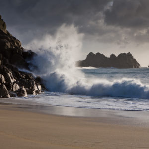 waves crashing against the rocks at Porthcurno Cove, Cornwall.