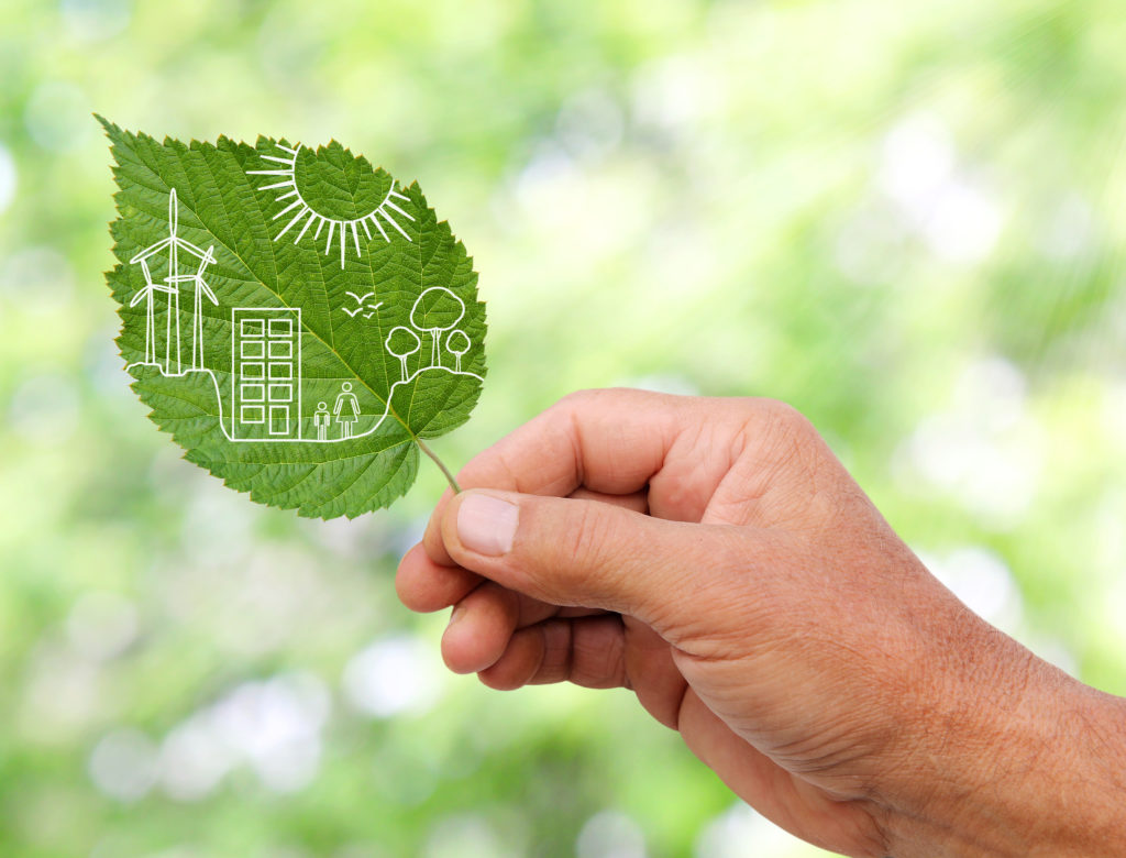 Hand holding a leaf with a Green city concept overlaid