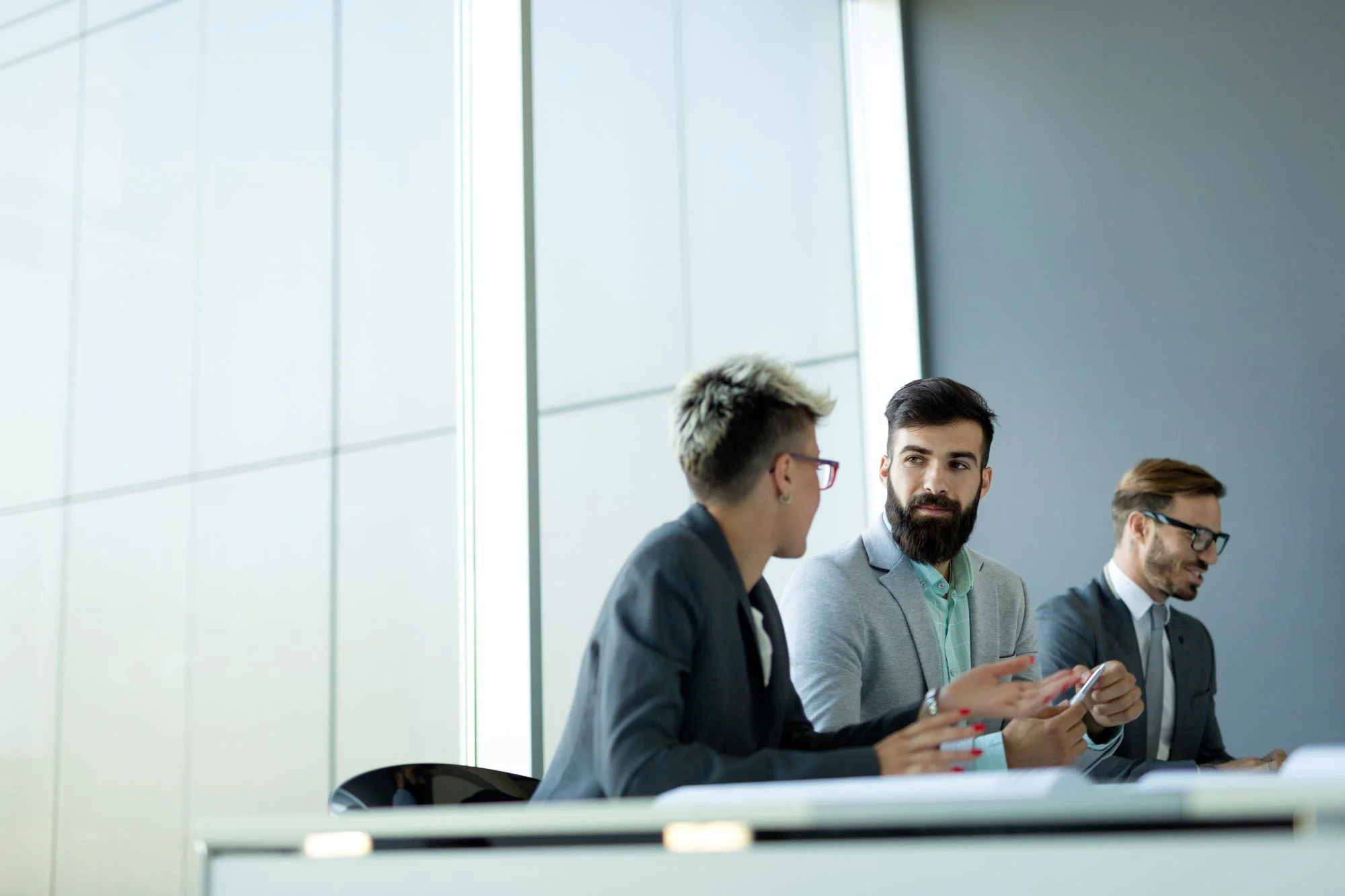 Meeting taking place in a modern office between one woman and two men