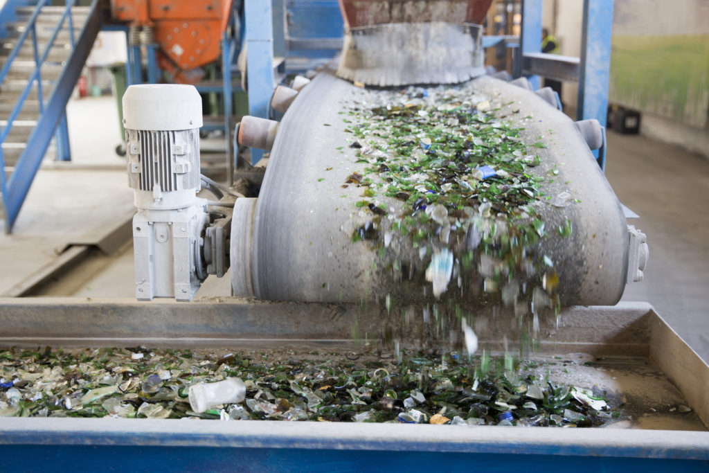 Glass particles for recycling in a machine in a recycling facility. Different glass packaging bottle waste. Glass waste management. Glass recycling is the process of waste glass into usable products.