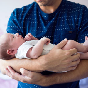 Close up of young father holding his newborn baby son in his arms