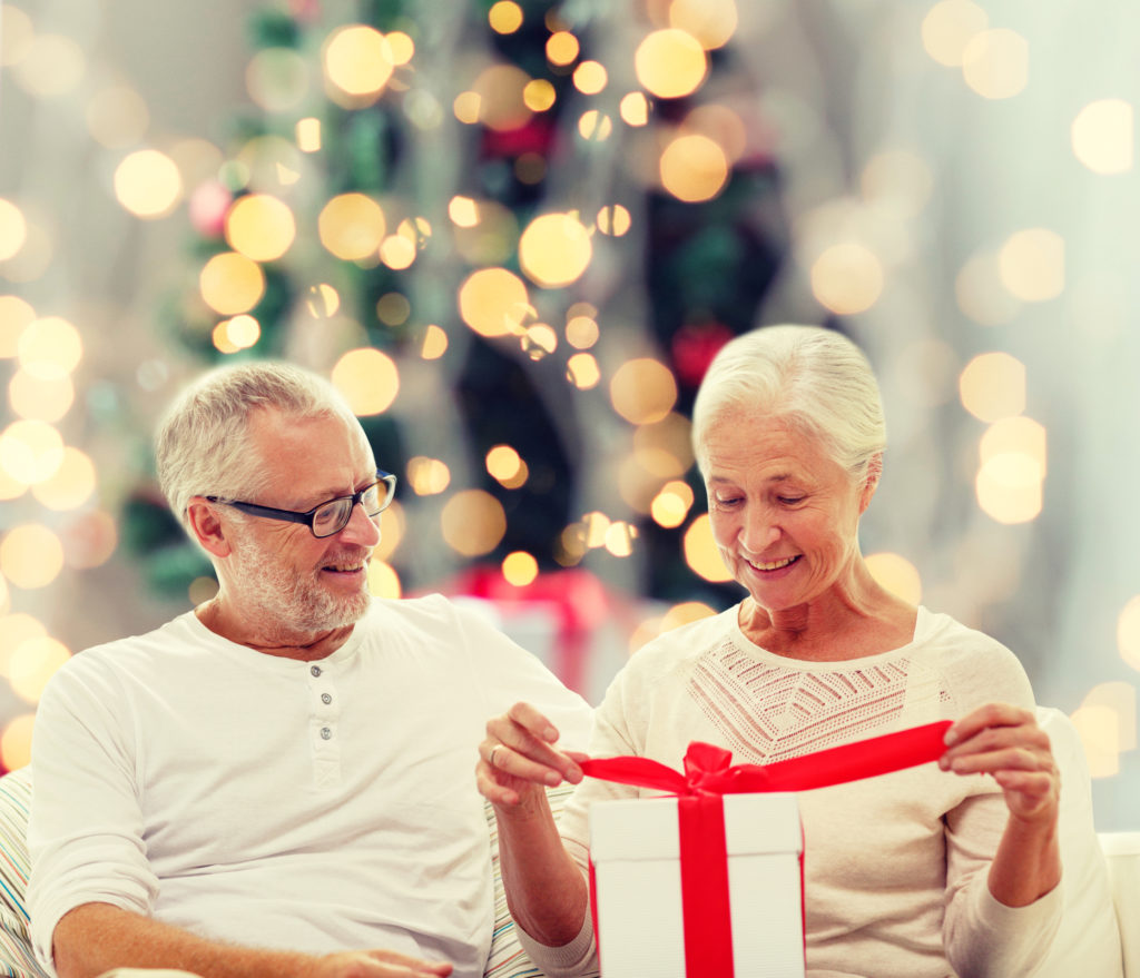 happy senior couple opening a christmas gift box at home