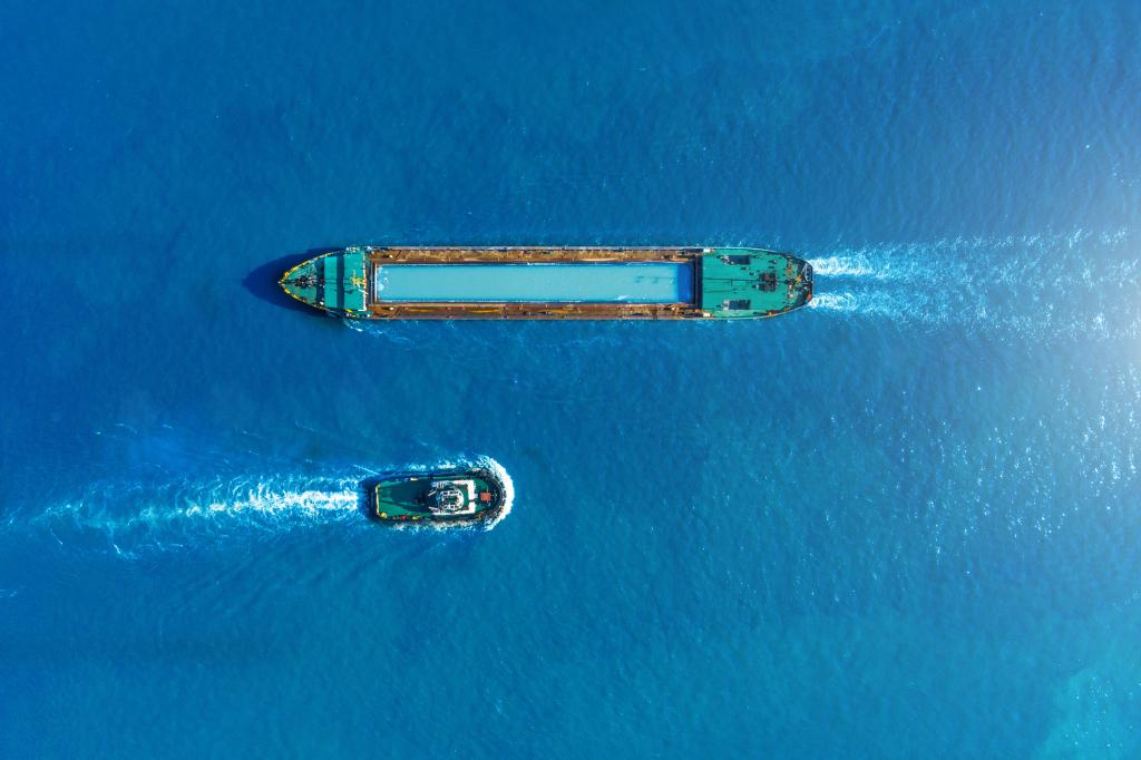 Cargo ship barge and tugboat sail to meet each other in the seaport of the port