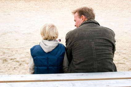 father and son sitting on a sandy beach talking
