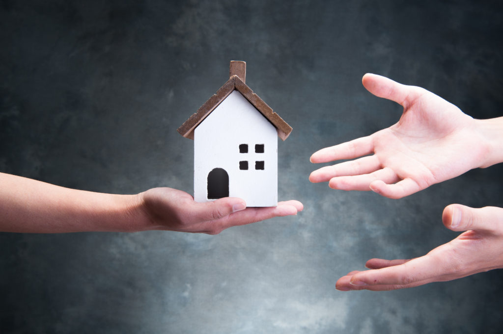 Residential image, hands holding a model house