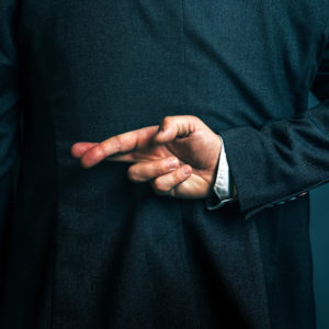 Lying businessman holding fingers crossed behind his back