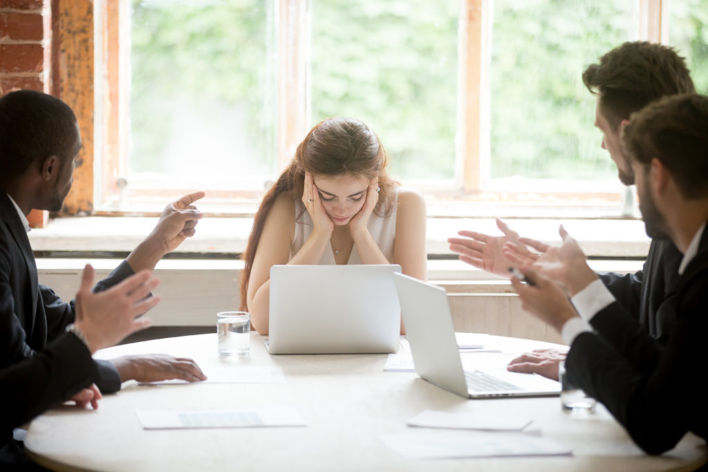 Male colleagues pointing fingers at upset female boss on meeting