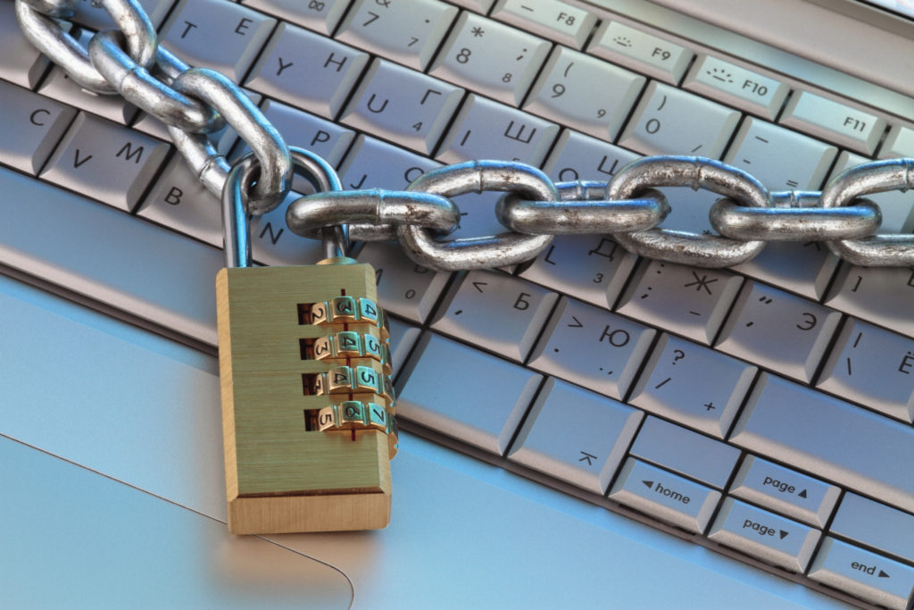 A padlock and a keyboard resting on a wooden table.