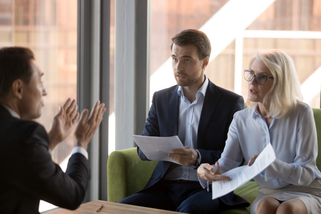 Angry financier director pointing on document showing it to colleague