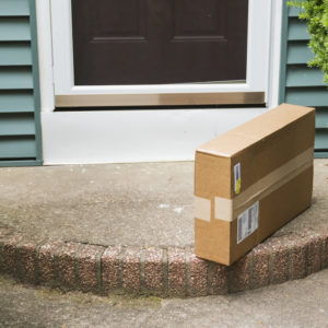 A brown cardboard box is left on the front stoop after being delivered while no one was home.