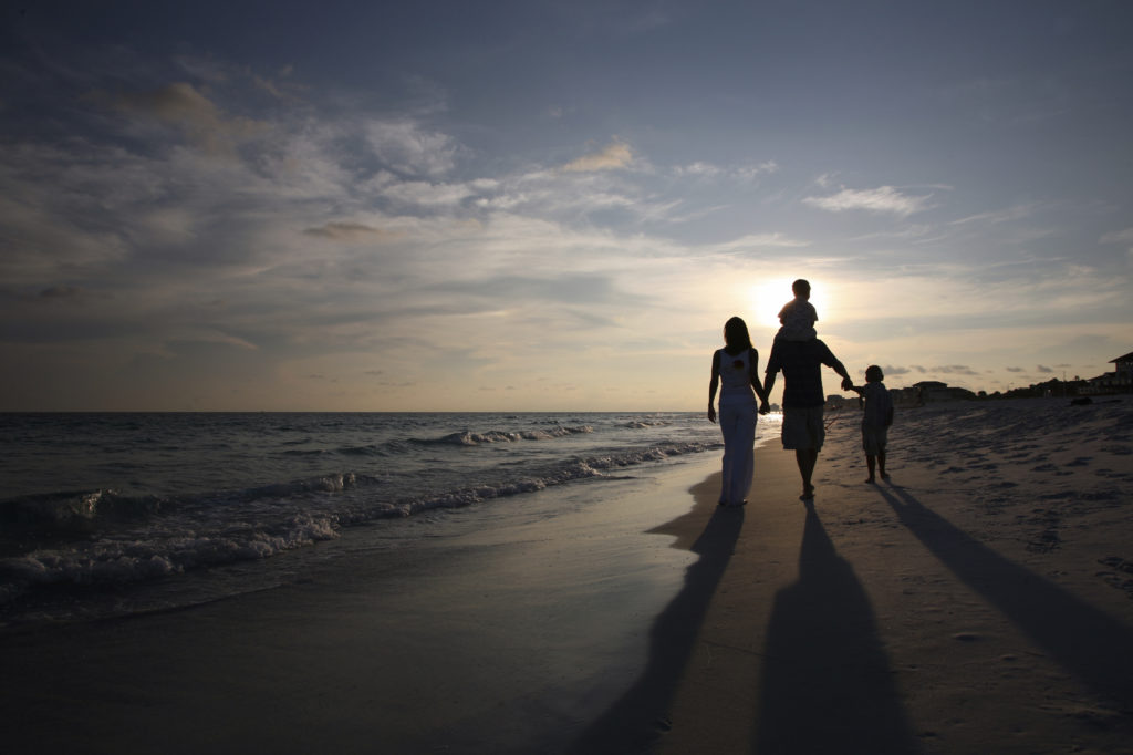 family waling together along the beachside during sunset