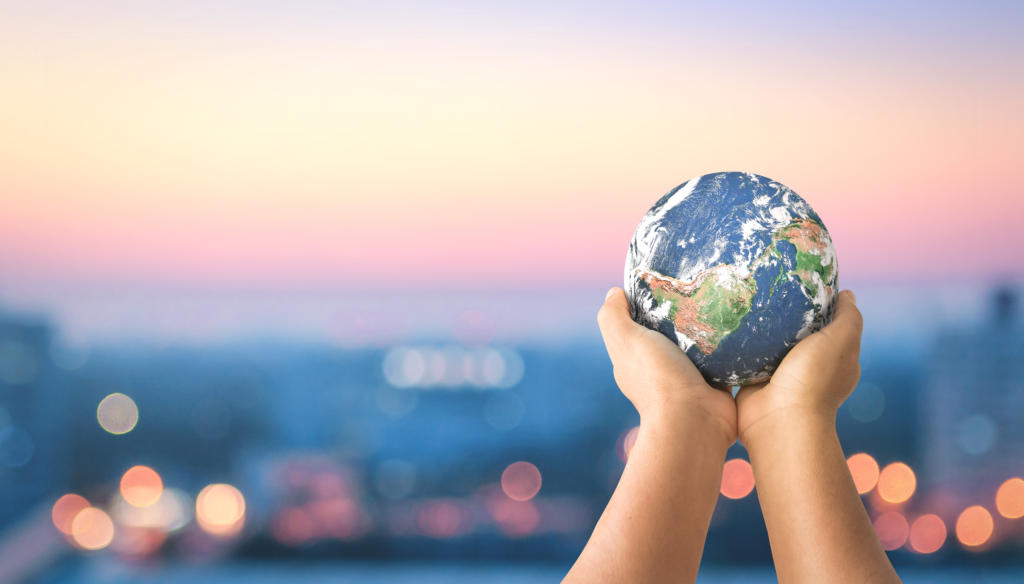 Human hands holding earth global over blurred city night background. Elements of this image furnished by NASA