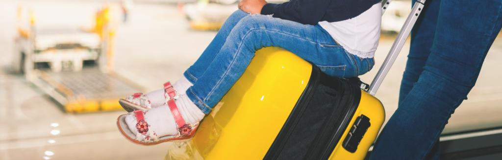 photo of a child sitting on airport luggage