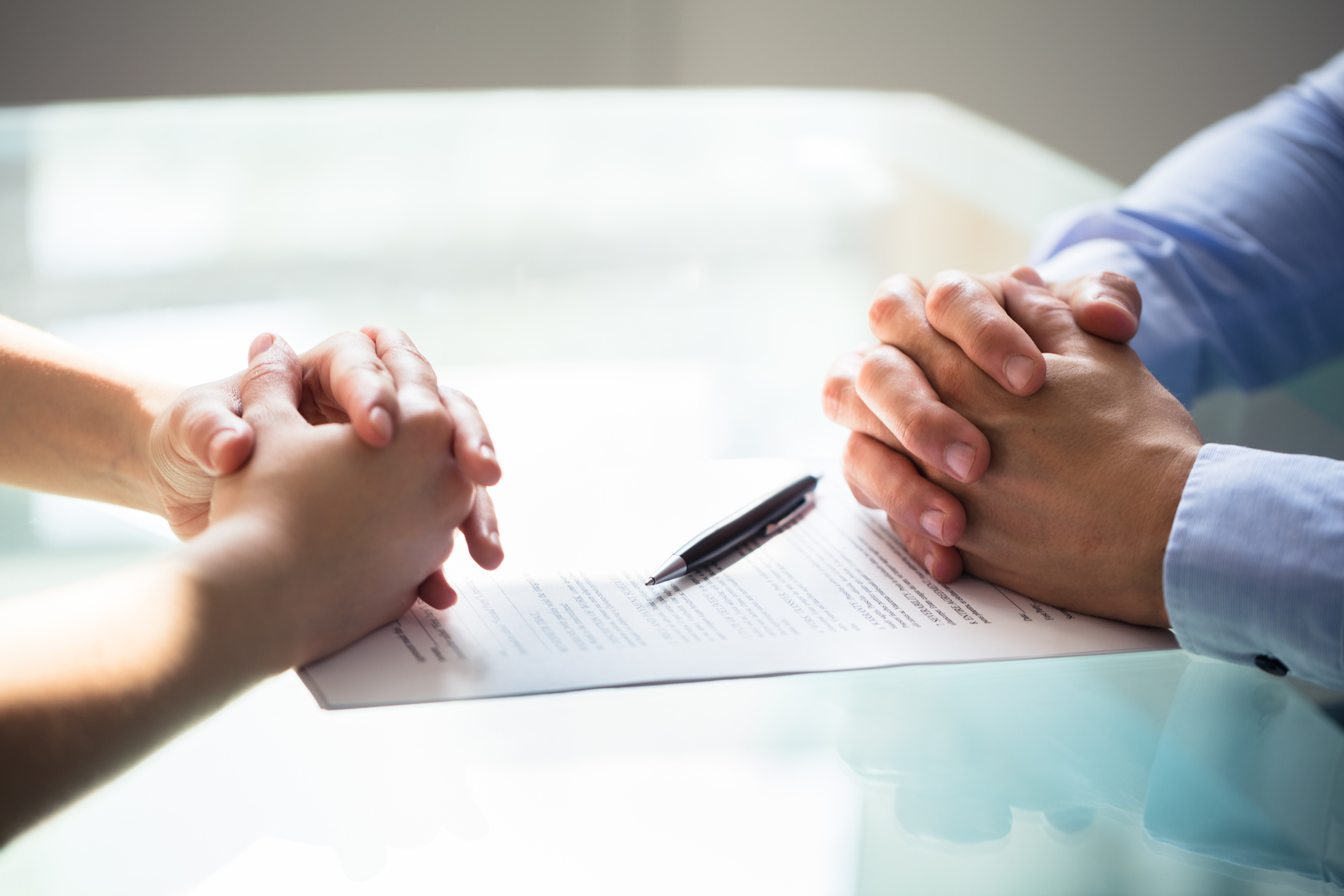 two peoples sets of hands on a table with a pen and document decree nisi