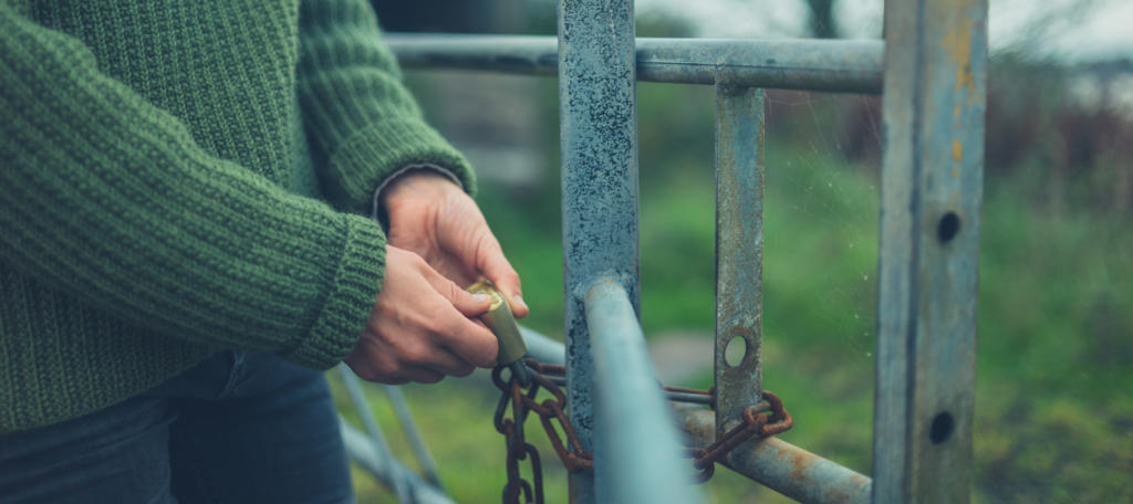 Young woman checking padlock on gate