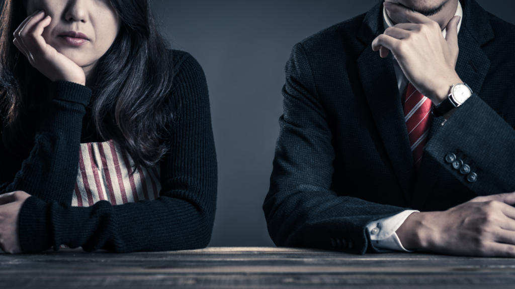 Woman wearing and apron and man wearing a suit. Both are considering an issue.