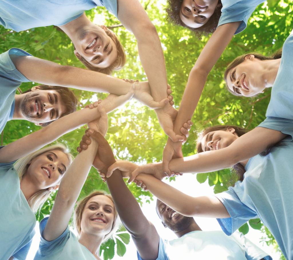 a group of happy volunteers outside linking hands