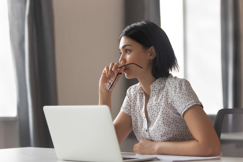 Adult woman using a laptop and looking away thoughtfully