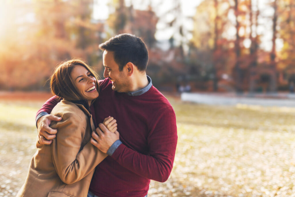 Couple in love hugging and enjoying a public park in autumn