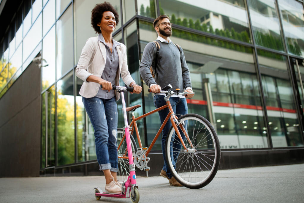 two happy people, one on a scooter and another on a bicycle, travelling to work without cars. concept for net zero