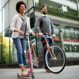 two happy people, one on a scooter and another on a bicycle, travelling to work without cars. concept for net zero