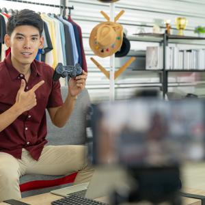 brand influencer holding up computer game controller in front of video captured on smart phone for marketing purposes