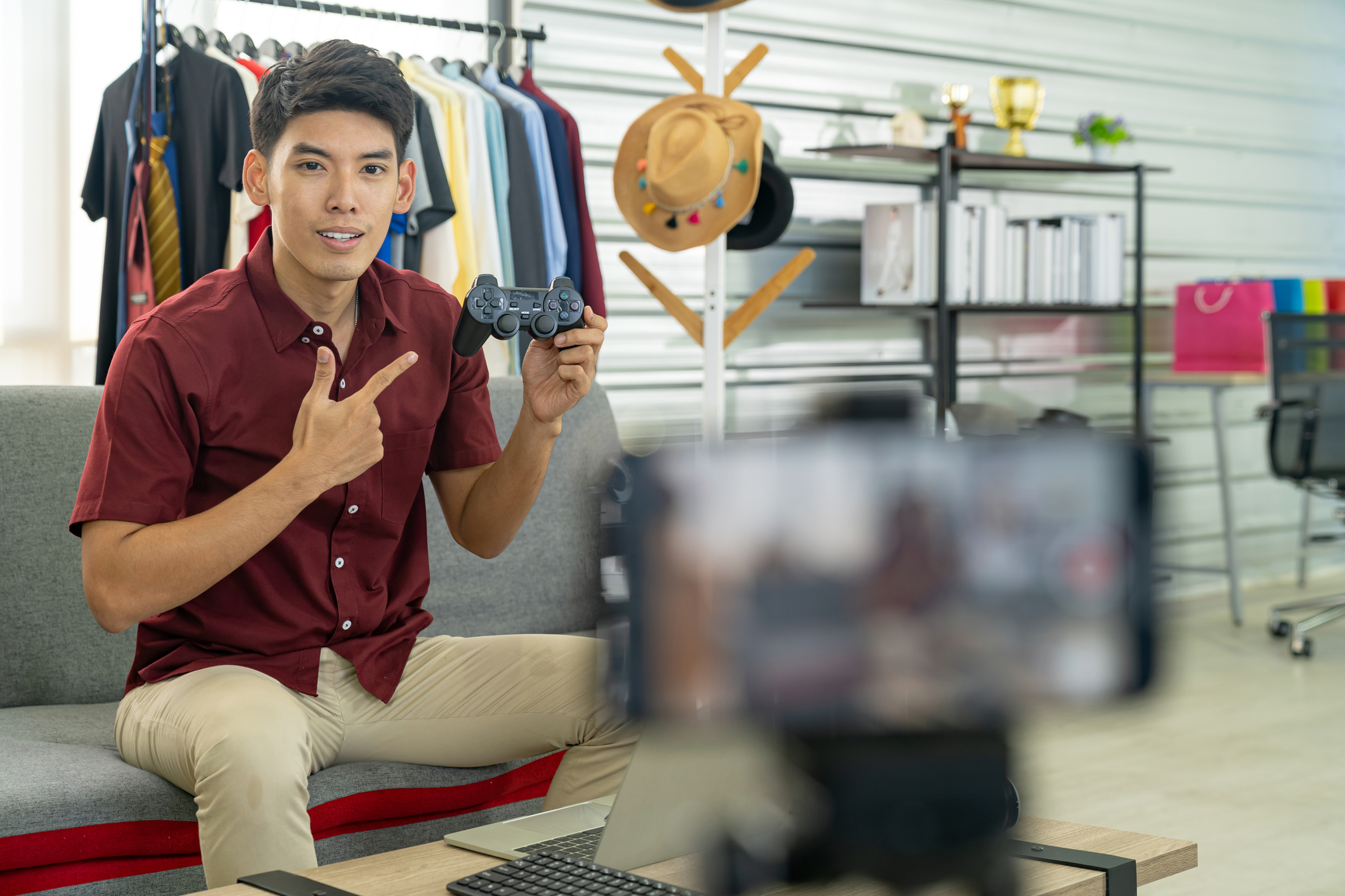 brand influencer holding up computer game controller in front of video captured on smart phone for marketing purposes