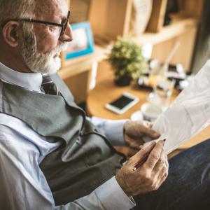 older man sitting in a chair reviewing document for a Inheritance 1975 Act claim