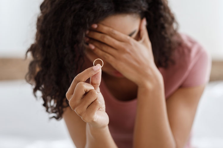 Person responds to adultery holds hand to forehead and wedding ring up in foreground