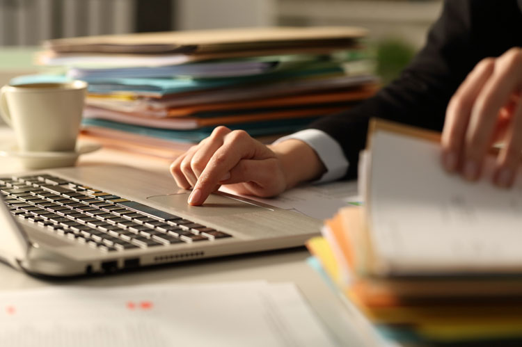 Person reviews professional negligence claim paperwork on desk with a laptop