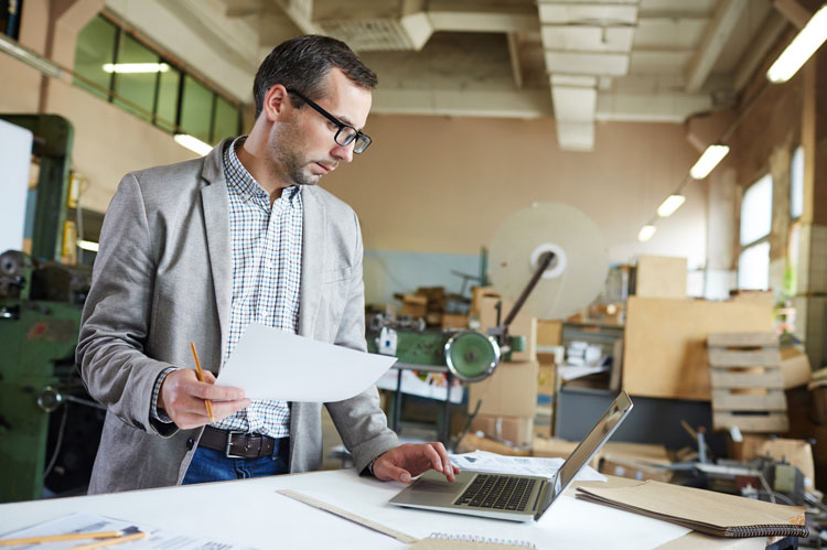 business owner in workshop reviewing intellectual property for smes on laptop