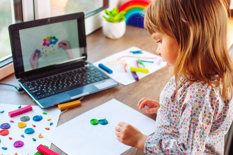 child moulding colourful clay cloud with rain watching online learning lesson