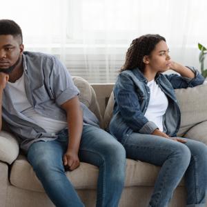 divided man and woman sit facing away from each other discussing divorce asset split