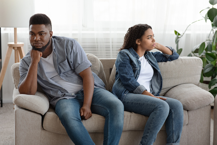 divided man and woman sit facing away from each other discussing divorce asset split