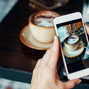 food and drink blogger taking picture of cup of coffee on smart phone
