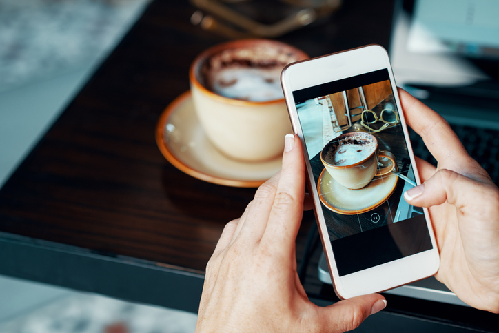 food and drink blogger taking picture of cup of coffee on smart phone