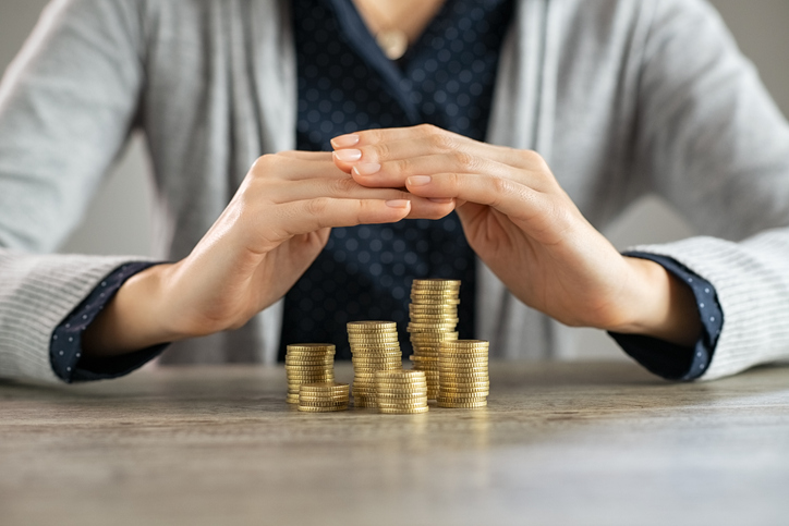 Woman with hands arched over coins, representing protecting assets in her sole name