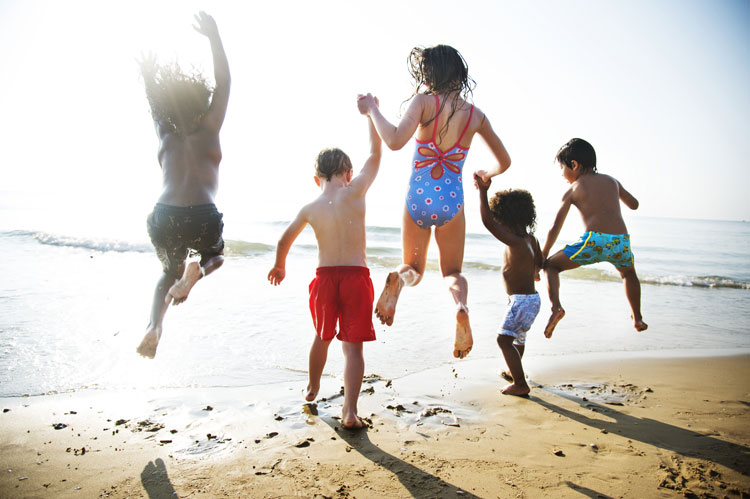 Group of children on holiday jumping in the air on a beach