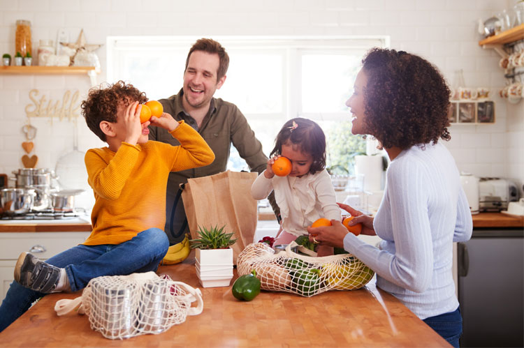 family in kitchen children and shopping bags sit on kitchen island surface - concept: introducing new partners to children