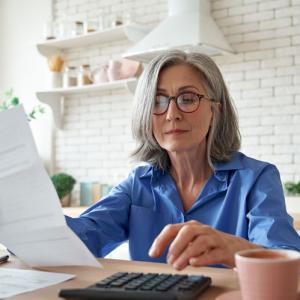 person holding paperwork about their entitlement to spouses pension on divorce using calculator